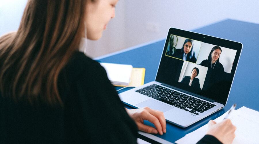 A person on a laptop video call with three colleagues